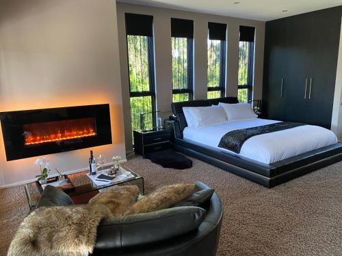 a bedroom with a king sized bed and a fireplace at Amarè Beachside Luxury in Turners Beach