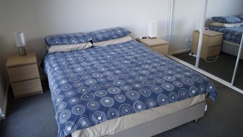 a bedroom with a bed with a blue comforter at Canberra CBD Metropolitan in Canberra