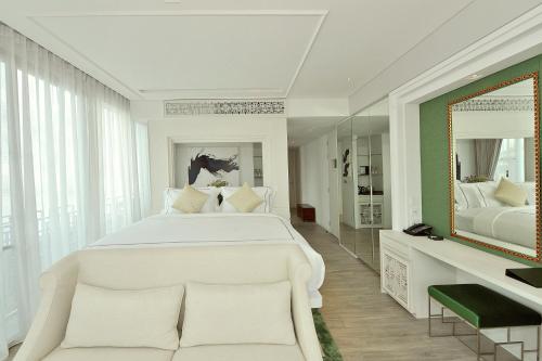 a bedroom with a large white bed and a mirror at Riva Arun Bangkok in Bangkok