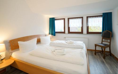 ein Schlafzimmer mit einem großen weißen Bett und einem Stuhl in der Unterkunft Dünenblick 4 Personen Strandnähe ruhig gelegen in Westerland