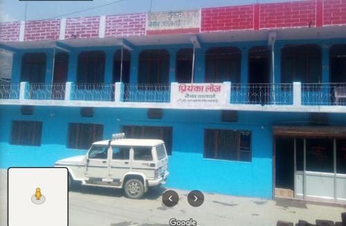 um camião branco estacionado em frente a um edifício azul em Priyanshu Lodge em Kharsālī