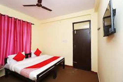 um quarto com uma cama com almofadas vermelhas e uma porta em Priyanshu Lodge em Kharsālī