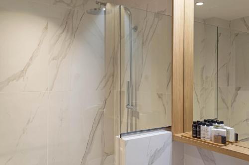 a shower in a bathroom with white marble walls at Eco Green Residences & Suites in Toroni