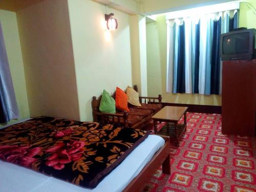 ein Hotelzimmer mit einem Bett und einem TV in der Unterkunft Very Homely Hotel for Tourists in Gangtok