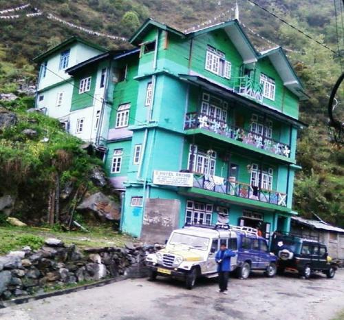 Ein blaues Haus mit einem Mann davor. in der Unterkunft Very Homely Hotel for Tourists in Gangtok
