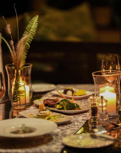a table with plates of food and candles on it at Khaya Ndlovu Safari Manor in Hoedspruit