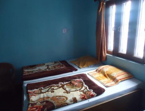 two beds in a blue room with a window at Hotel SHREE Uttarkashi in Uttarkāshi