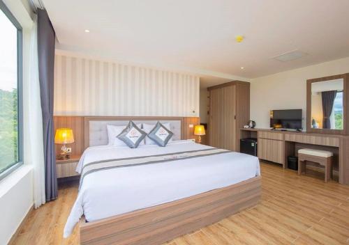 Un dormitorio con una cama grande y un televisor. en UMI-PQ hotel, en Phu Quoc