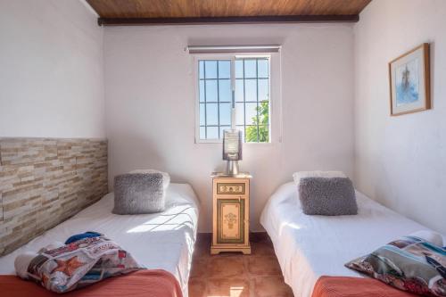 two twin beds in a room with a window at Casa Tabaiba - Villa Perenquén in Guía de Isora
