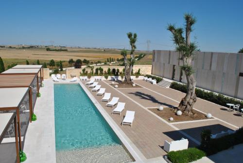 uma piscina com espreguiçadeiras e palmeiras num resort em Tenuta Danesi & Bubble Rooms em Matera
