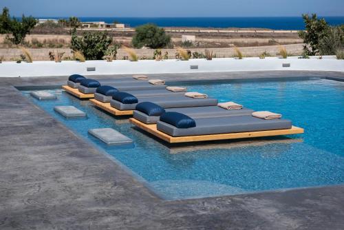 a row of chaise lounges in a swimming pool at Volcanic Arc Suites in Oia