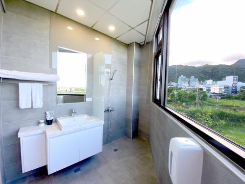礁溪鄉的住宿－秋水閣，一间带水槽和淋浴的浴室以及窗户。
