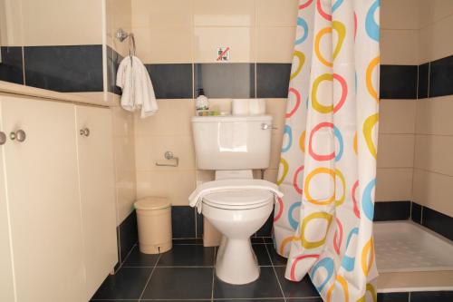 a small bathroom with a toilet and a shower curtain at West End Hotel in Peyia
