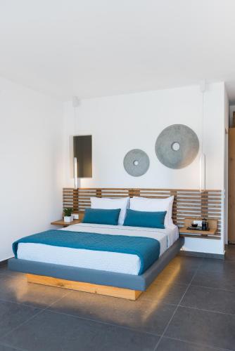 a bedroom with a large bed with blue pillows at Volcanic Arc Suites in Oia