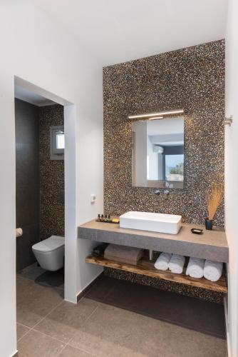a bathroom with a sink and a mirror at Volcanic Arc Suites in Oia