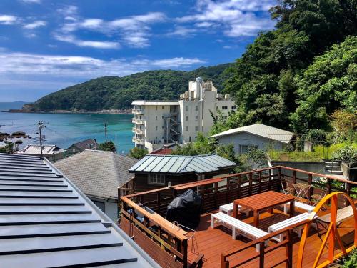 balcón con mesa, sillas y vistas al agua en Guesthouse All you need en Shimoda