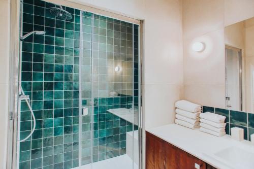 La salle de bains est pourvue d'une douche carrelée de couleur verte et d'un lavabo. dans l'établissement Joie Paris Arc de Triomphe - Champs Elysée, à Paris