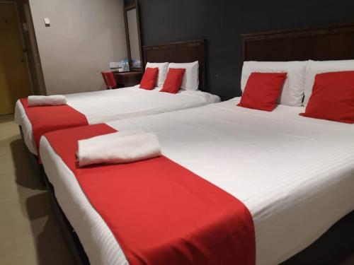 2 letti con lenzuola rosse e bianche in una stanza di NICE STAY HOTEL a Raub