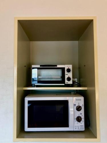 a kitchen with a microwave and a toaster oven at Guesthouse All you need - All rooms have an ocean view! in Shimoda