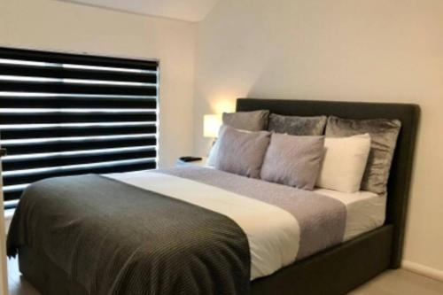 um quarto com uma cama grande com almofadas e uma janela em Spacious & Luxurious 1 bed House in Thamesmead em Thamesmead