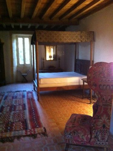 une chambre avec un lit à baldaquin et une chaise dans l'établissement gite des rois ducs, à Sauveterre-la-Lémance
