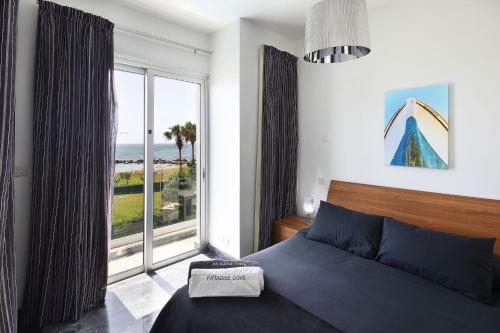 een slaapkamer met een bed en een groot raam bij Paradise Cove Luxurious Beach Villas in Paphos City