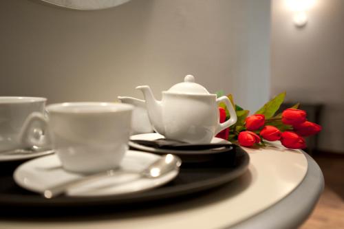 a table with two cups and a tea pot and flowers at Vinoteca La Sacrestia in Alba