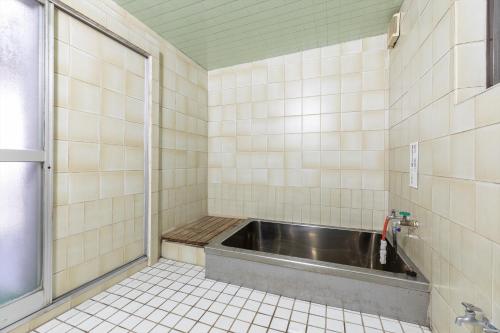 a bathroom with a bath tub in a tiled room at Tabist Futaba Ryokan Tatsuno in Tatsuno