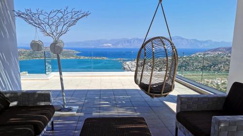 a porch with a swing and a view of the ocean at Villa Estée, luxury villa with private infinity pool and jacuzzi in Elounda
