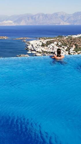a person swimming in a pool of blue water at Villa Estée, luxury villa with private infinity pool and jacuzzi in Elounda