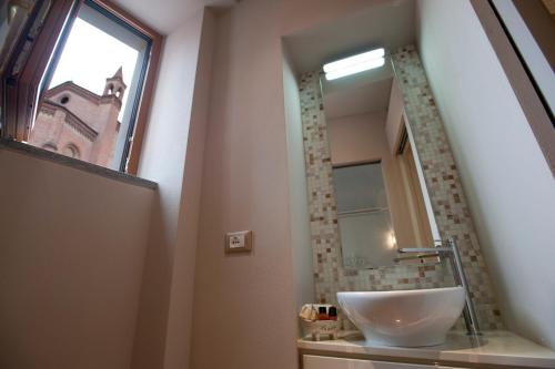 a bathroom with a sink and a window and a mirror at Vinoteca La Sacrestia in Alba