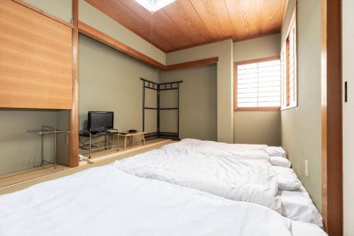a large white bed in a room with a window at Tabist Futaba Ryokan Tatsuno in Tatsuno