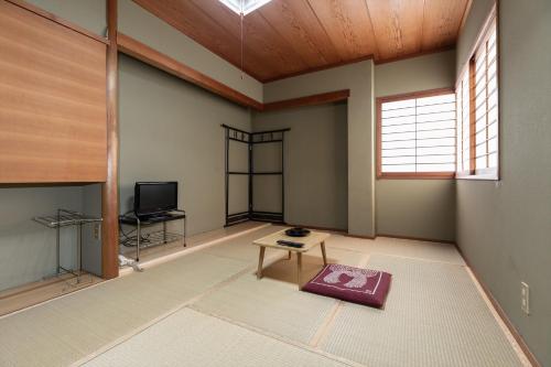 a living room with a table and a tv at Tabist Futaba Ryokan Tatsuno in Tatsuno