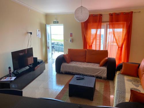 a living room with a couch and a flat screen tv at Apartamento acolhedor numa das mais belas praias do centro de Portugal in Pataias