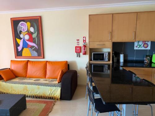 a living room with an orange couch and a kitchen at Apartamento acolhedor numa das mais belas praias do centro de Portugal in Pataias