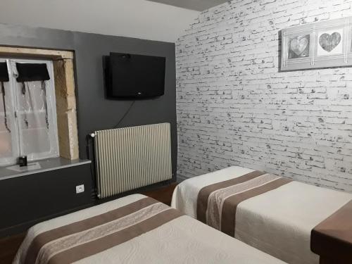 1 dormitorio con 2 camas y pared de ladrillo en Escampette, en Saint-Aubin-en-Charollais