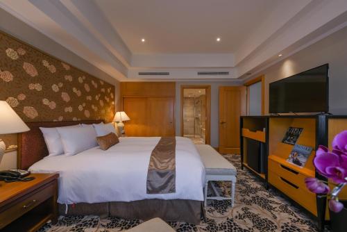 a hotel room with a bed and a flat screen tv at THE LEES Hotel in Kaohsiung