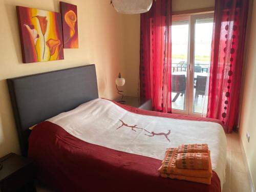 ein Schlafzimmer mit einem Bett mit roten Vorhängen und einem Fenster in der Unterkunft Apartamento acolhedor numa das mais belas praias do centro de Portugal in Pataias