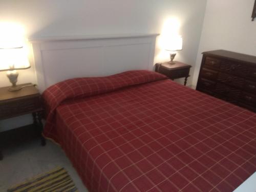 アルマカオ・デ・ペラにあるBeira Mar Terrace Apartmentのベッドルーム1室(赤いベッド1台、ランプ2つ、テーブル2台付)