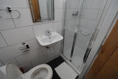 a bathroom with a shower and a toilet and a sink at Holland Inn Hotel in London