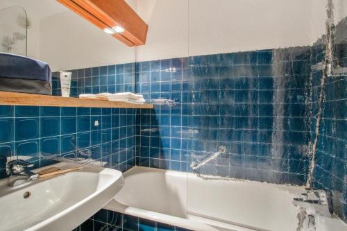 La salle de bains est pourvue de carrelage bleu, d'une baignoire et d'un lavabo. dans l'établissement Pierre et Vacances Serre Chevalier Chantemerle, à Saint-Chaffrey
