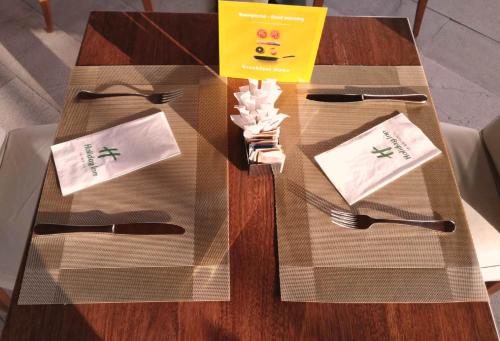 a table with a glass table with utensils on it at Holiday Inn Cagliari by IHG in Cagliari