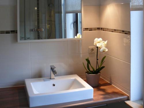 baño con lavabo blanco y jarrón de flores en Ferienhaus Villa Bourguet en Bad Liebenstein