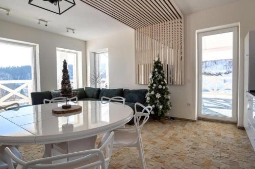 a living room with a table and a christmas tree at Шале БІЛИЙ ЛЕВ - WHITE LION Chalet in Bukovel