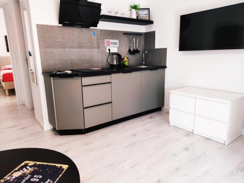 a kitchen with white cabinets and a flat screen tv at PALAIO FALIRO SUITE DELUX NEAR THE SEa in Athens