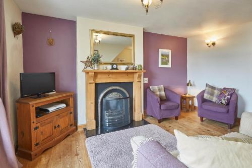 Il comprend un salon avec une cheminée et une télévision. dans l'établissement Host & Stay - Esk View Cottage, à Whitby