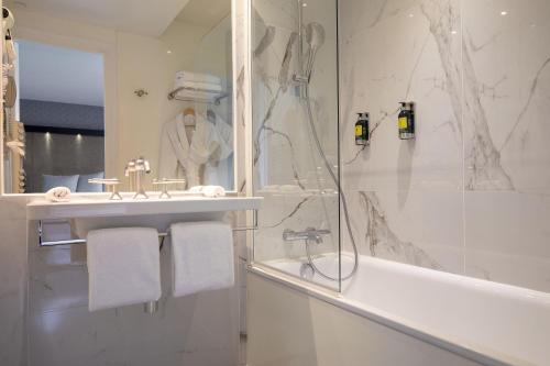 a bathroom with a shower and a sink and a tub at Hôtel Elysées Régencia in Paris