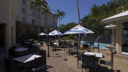 a patio area with tables, chairs and umbrellas at The Riverside Hotel in Durban