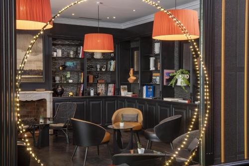 a restaurant with a fireplace and chairs and lights at Hôtel Elysées Régencia in Paris