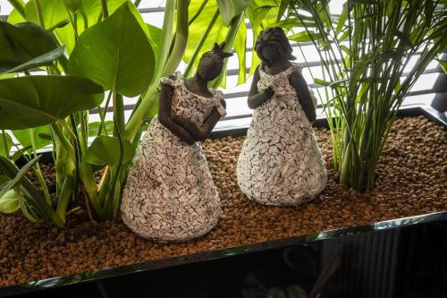 two statues of two women standing in a plant at Hôtel Elysées Régencia in Paris